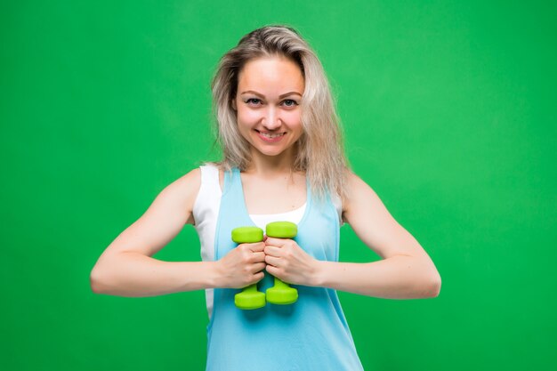 Niña en ropa deportiva con pesas en una pared verde, espacio para texto