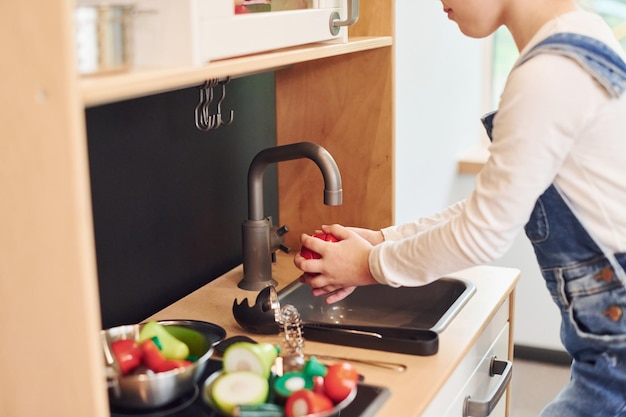 Foto una niña con ropa informal se divierte jugando con juguetes en la cocina