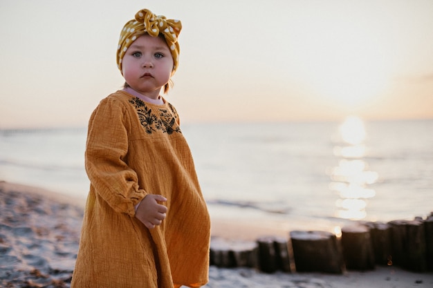 Niña en ropa oriental caminando por la playa al atardecer