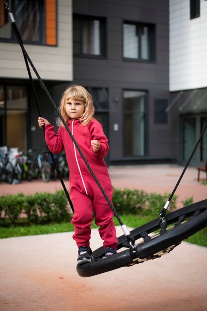 niña en ropa roja columpiándose en un columpio