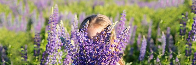 Niña sin rostro con ramo de flores de altramuces en un campo niña con altramuces morados Concepto de niño en la naturaleza