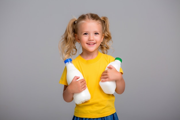 niña rubia con botellas de plástico de leche