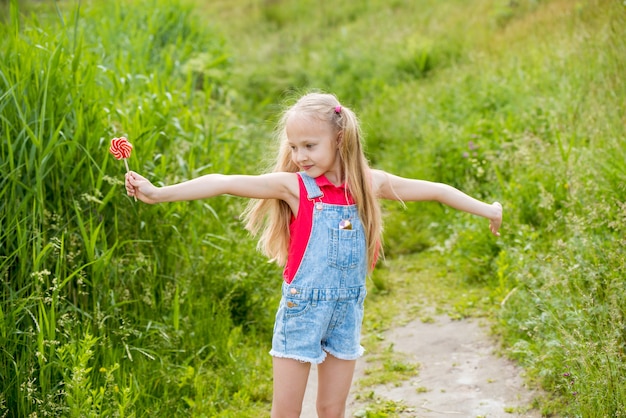 Niña rubia con cabello largo y dulces en un palo en la mano