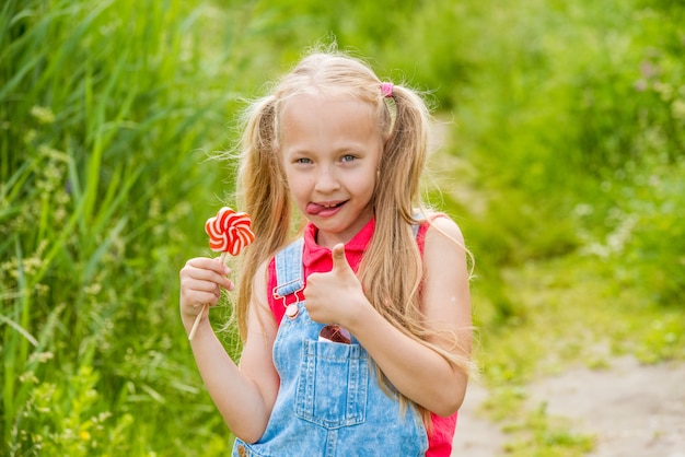 Niña rubia con cabello largo y dulces en un palo