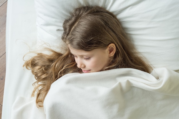 Niña rubia con cabello largo y ondulado durmiendo