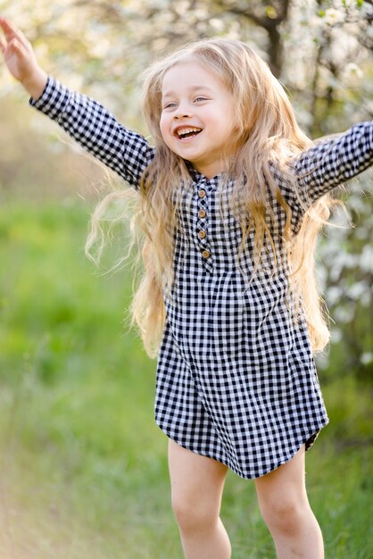 Niña rubia divirtiéndose en el parque de la primavera.