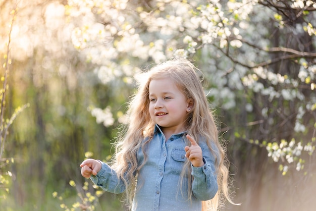 Niña rubia divirtiéndose en el parque de la primavera.