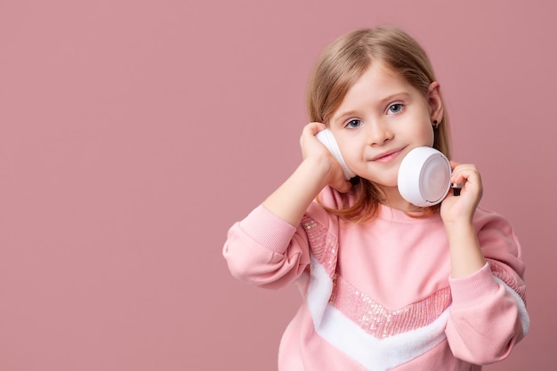 Una niña rubia escucha música con auriculares.