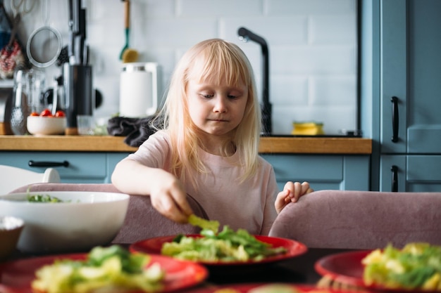 Niña rubia está ayudando a preparar la cena en la cocina