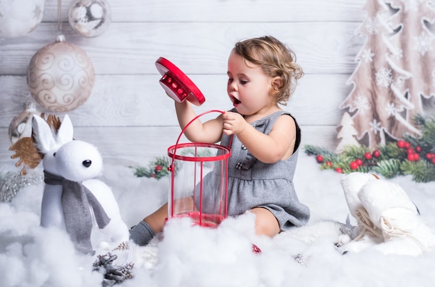 Niña rubia está jugando en la decoración de invierno de Navidad.