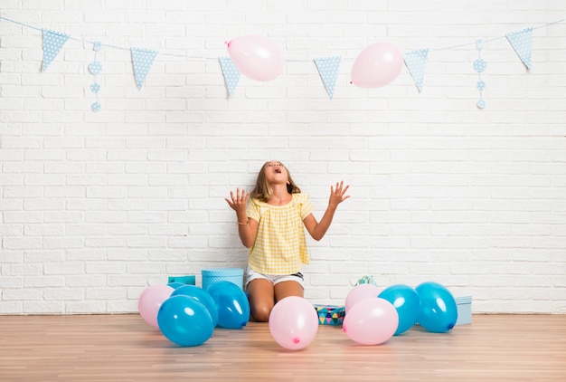 Niña rubia en una fiesta de cumpleaños jugando con globos