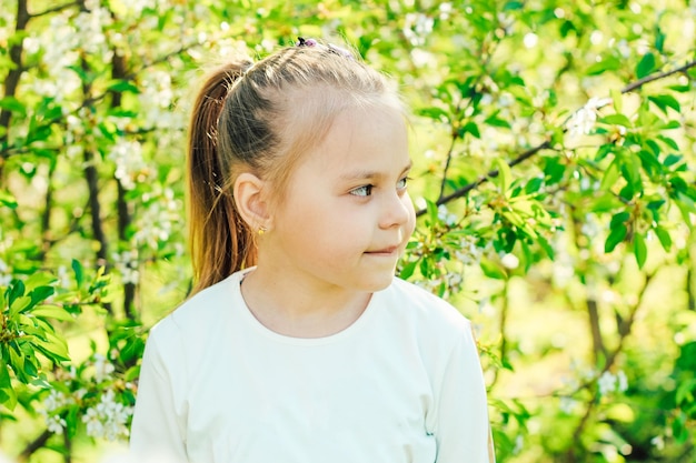 Niña rubia en el fondo de árboles en flor