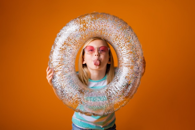 Niña rubia con gafas de sol tiene un círculo de natación en sus manos