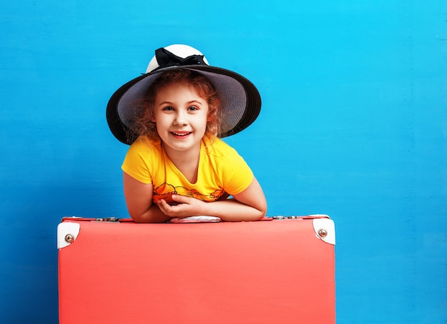 Niña rubia con maleta vintage rosa lista para las vacaciones de verano. Concepto de viajes y aventuras.