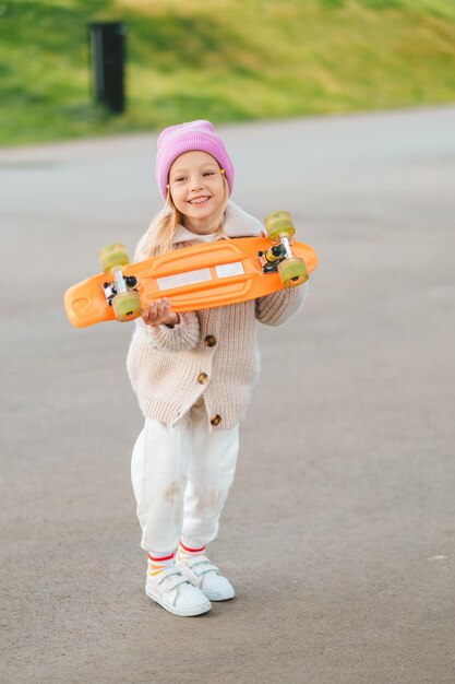 una niña rubia monta una patineta una niña elegante ríe y patina