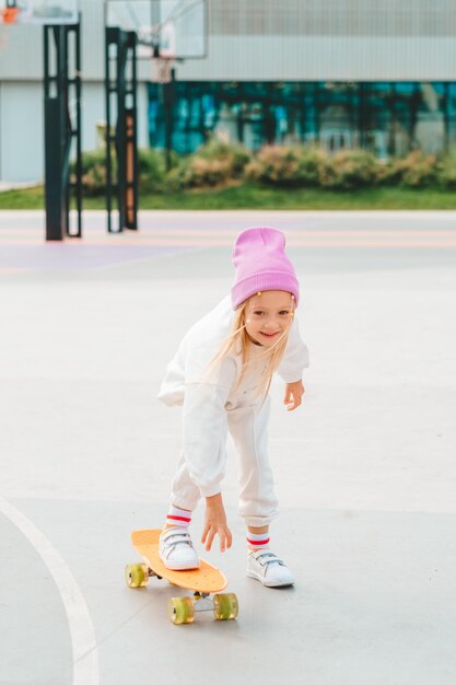 una niña rubia monta una patineta patinaje inseguro sin protección