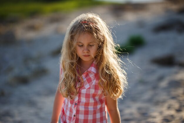 Niña rubia niño caminando en la playa de verano al atardecer.