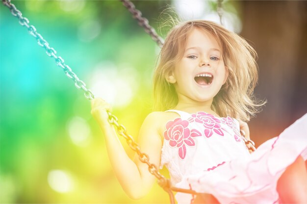 Niña rubia niño divirtiéndose en un columpio