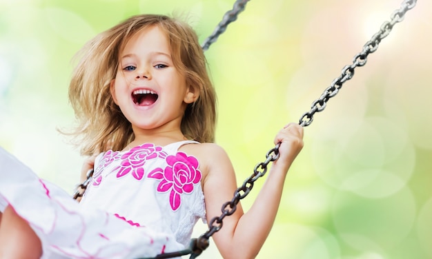 Niña rubia niño divirtiéndose en un columpio