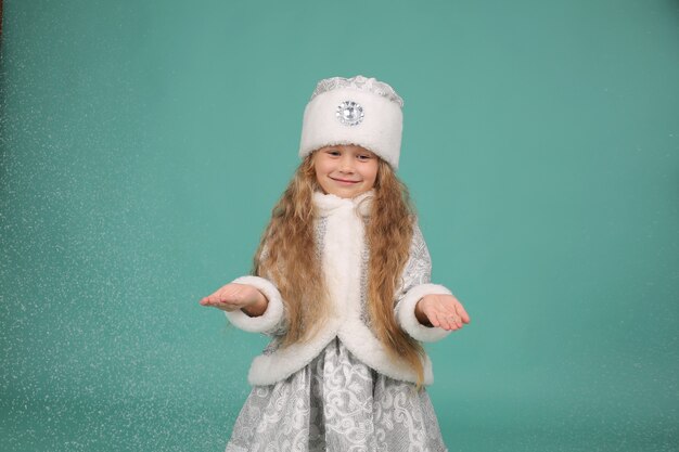 una niña rubia con ojos azules en un traje de doncella de nieve de Año Nuevo nieve artificial