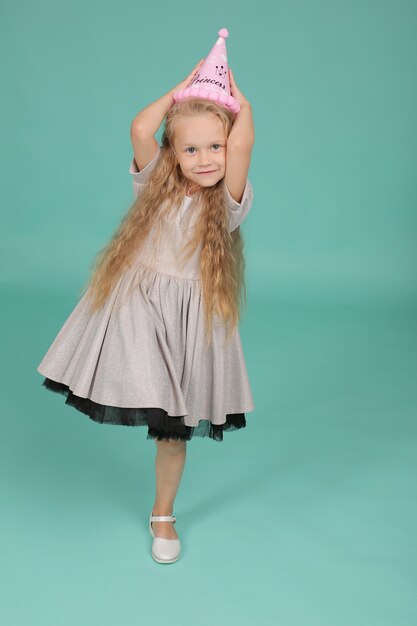 niña rubia con ojos azules en un vestido gris con un sombrero feliz cumpleaños