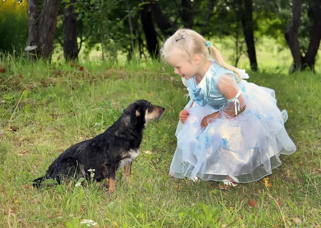 Una niña rubia con un perro en el jardín de verano