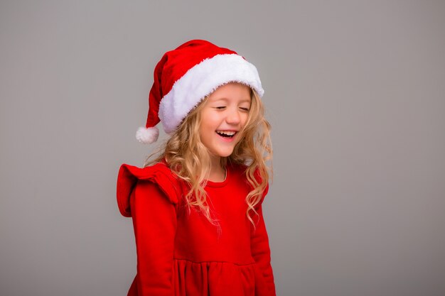 Niña, la rubia sonríe con un sombrero de Santa en