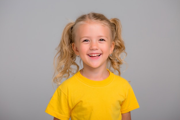 Niña rubia sonriendo sobre fondo claro