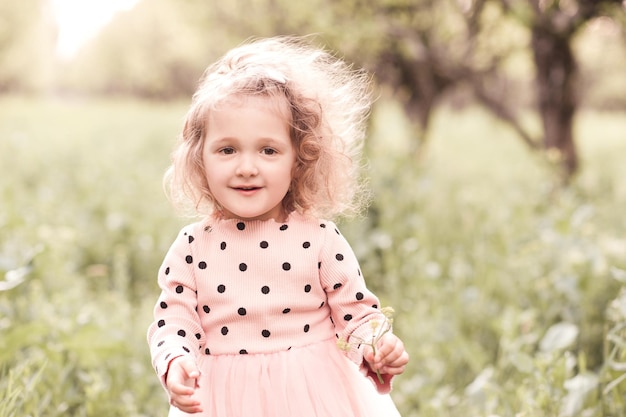 Niña rubia sonriente posando al aire libre de cerca