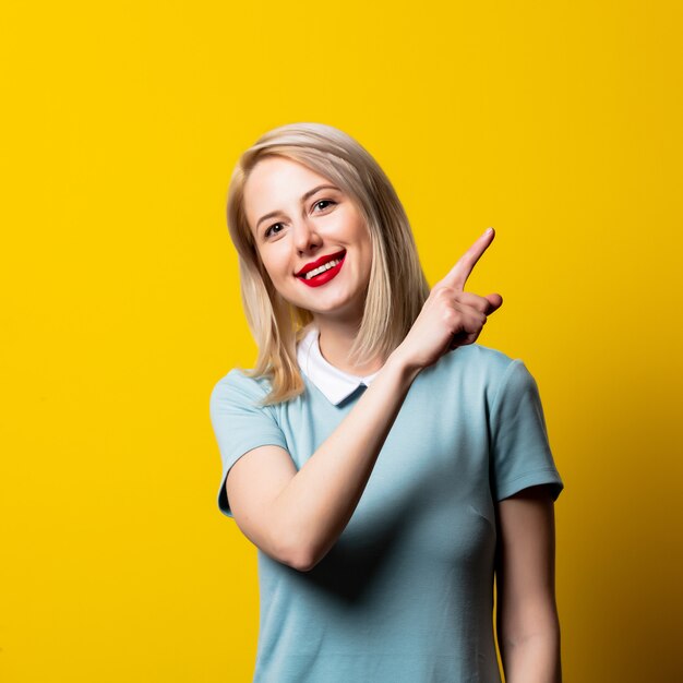 Niña rubia sonriente en vestido azul en espacio amarillo