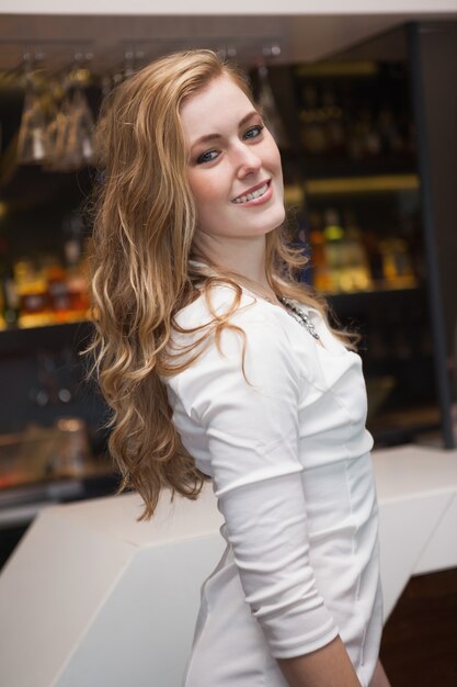 Niña rubia sonriente en vestido blanco posando