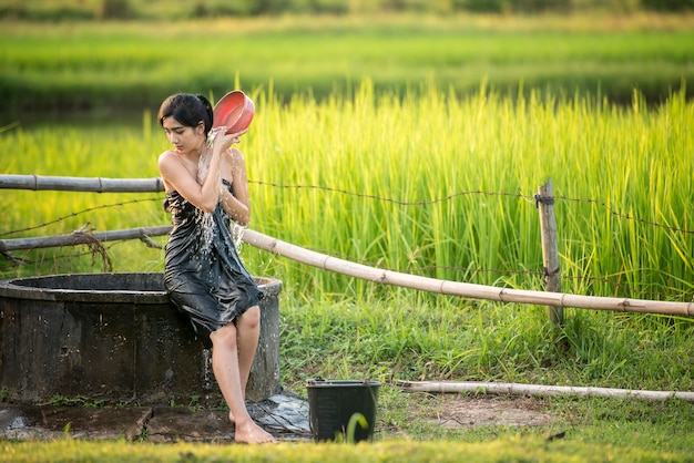 Niña rural está tomando una ducha de un agua subterránea tradicional