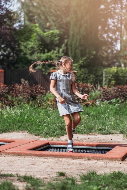 Niña salta en trampolín en un parque Niño riendo feliz al aire libre en el patio en vacaciones de verano Saltar alto