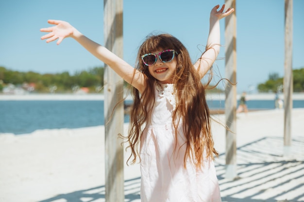 Niña saltando en la playa a orillas de la playa de la ciudad en las vacaciones de verano