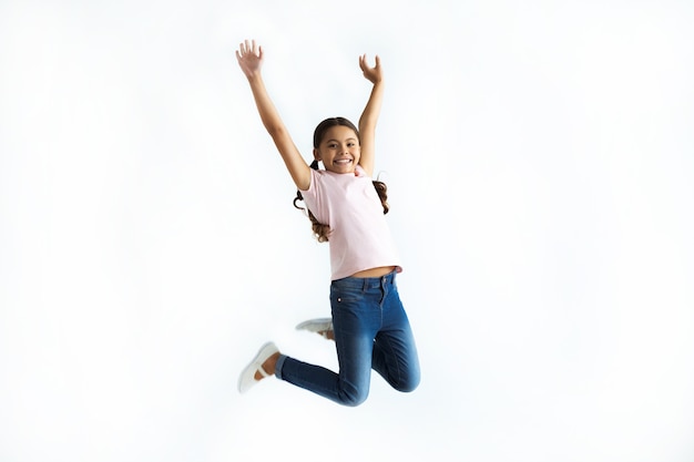 Foto la niña saltando sobre el fondo de la pared blanca