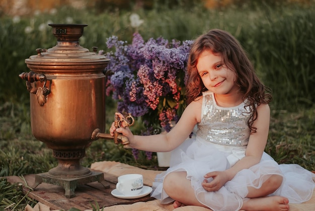 una niña con un samovar y lila flores lilas samovar una niña con un vestido té