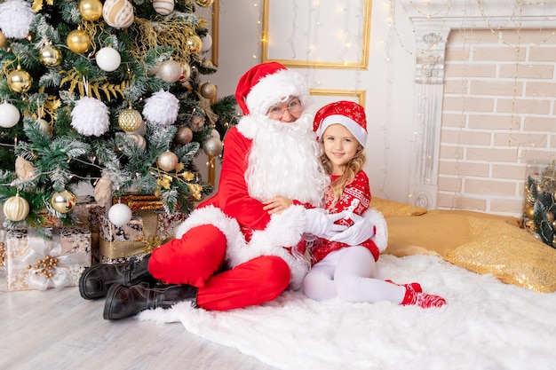 Niña con Santa Claus en el árbol de Navidad, año nuevo y concepto de Navidad