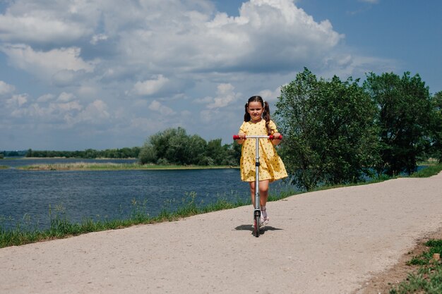 Una niña en un scooter un fin de semana familiar en un mini viaje local un scooter para niños como símbolo de la familia ...