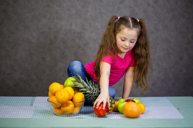 Una niña de seis años ama mucho las frutas. Vitaminas y alimentación saludable.