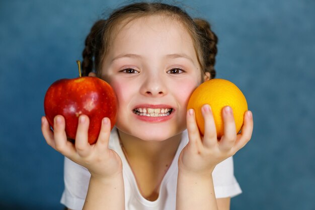 Una niña de seis años ama mucho las frutas. Vitaminas y alimentación saludable.