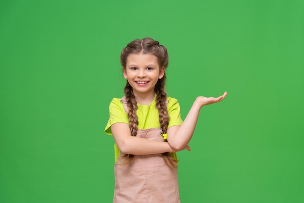 La niña señala hacia un lado y sonríe. Niños en un fondo aislado.