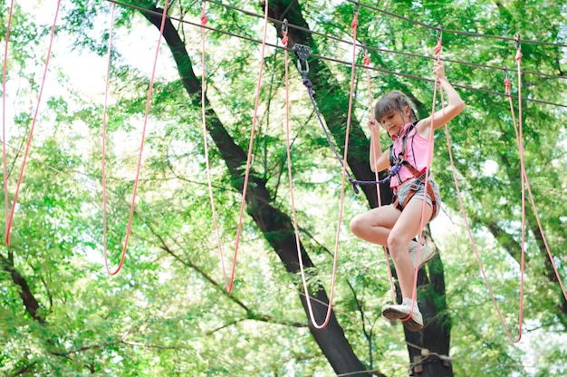 Niña de senderismo en el parque de cuerdas en equipos de seguridad