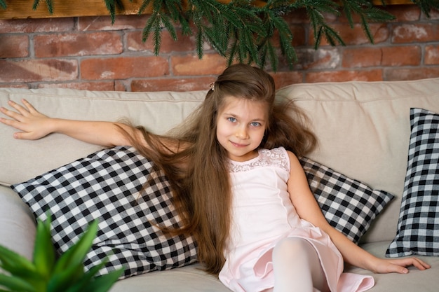 Niña sentada en un acogedor sofá con almohadas a cuadros