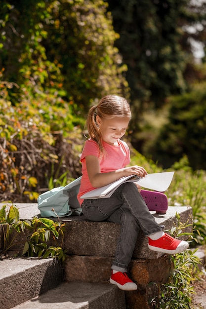 Una niña sentada afuera con libros y preparando lecciones.