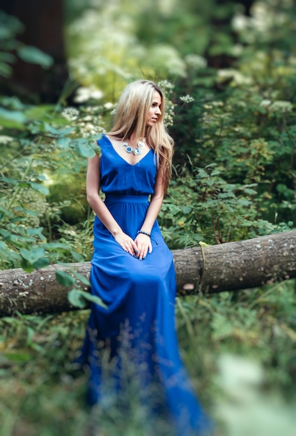 Foto niña sentada en un árbol con un vestido largo