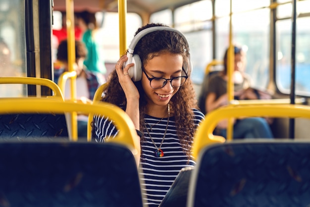 Foto niña sentada en un autobús, escuchando música.