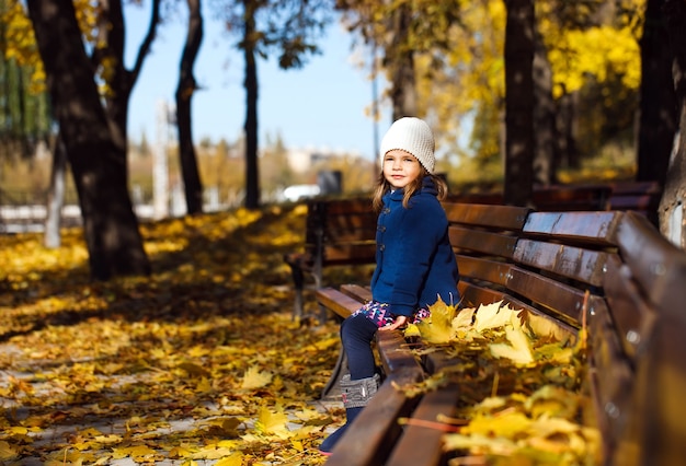 Niña sentada en un banco en el parque