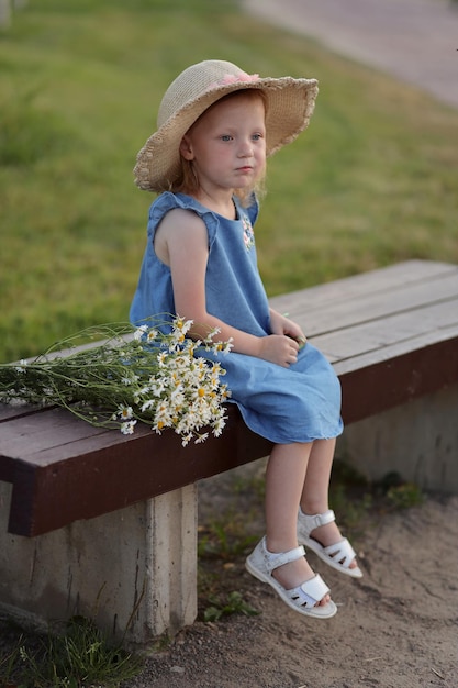 niña sentada en un banco con un ramo de flores