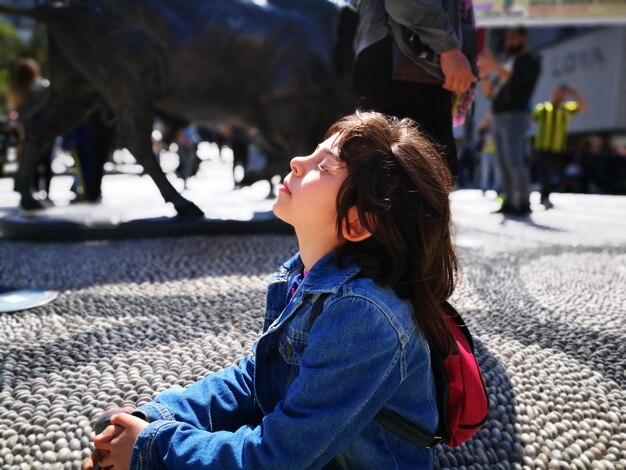 Foto niña sentada en el camino en la ciudad