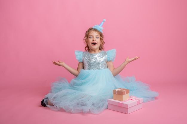 niña sentada celebrando cumpleaños con fondo rosa, hermoso vestido de princesa